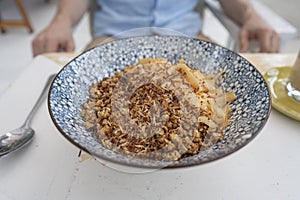 Bowl with granules and coconut and chocolate chips for a healthy breakfast. Male hand with a spoon and a plate with muesli