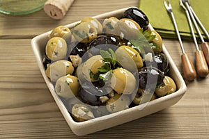 Bowl with green and black olives seasoned with garlic and herbs