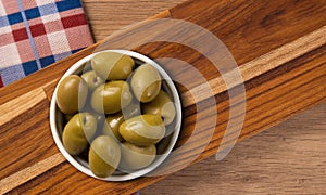 Bowl with green olives, on a wooden background. top view