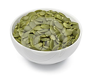 Bowl with green pumpkin seeds isolated on white background