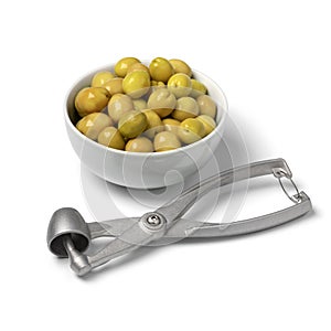 Bowl with green Turkish olives close up and a olive pitter in front on white background