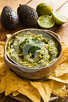 Bowl of guacamole dip with tortilla chips and ingredients in background