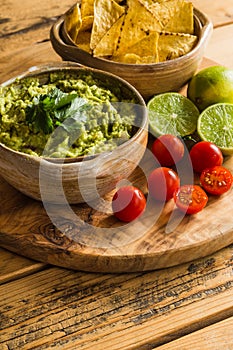 Bowl of guacamole dip with tortilla chips limes and cherry tomatoes