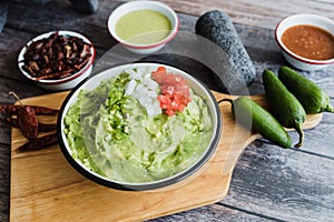 Bowl of Guacamole next to fresh ingredients on a wooden table in Mexico