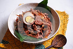 A bowl of gudeg Jogja with egg against white background