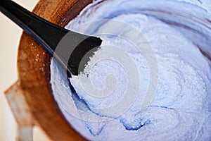 Bowl, hair dye and blue color in salon for haircare, paste and chemical for tint or bleach for grooming. Closeup