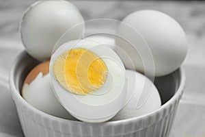 Bowl with hard boiled eggs on blurred background, closeup