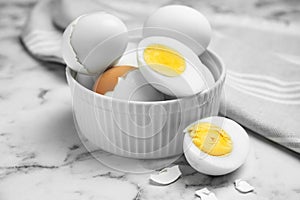 Bowl with hard boiled eggs on white marble table