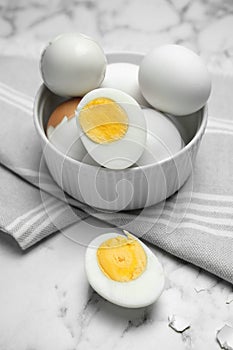 Bowl with hard boiled eggs on white marble table