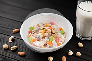 A bowl of healthy breakfast muesli with yogurt and nuts with glass of milk.