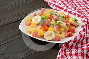 Bowl of healthy citrus fruit salad on dark wooden background