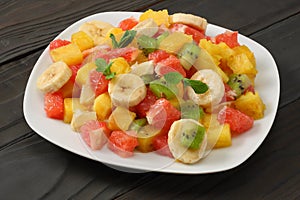 Bowl of healthy citrus fruit salad on dark wooden background. Top view.