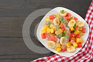 Bowl of healthy citrus fruit salad on dark wooden background. Top view.