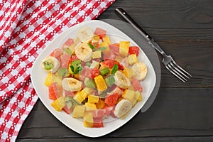 Bowl of healthy citrus fruit salad on dark wooden background. Top view.