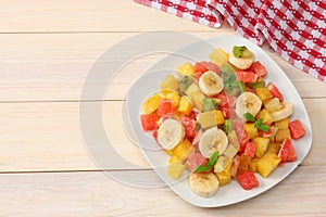 Bowl of healthy citrus fruit salad on light wooden background. Top view.