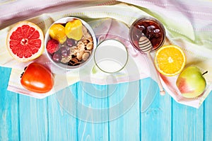 Bowl of healthy corn flakes breakfast cereal, milk and fruits on blue wood table