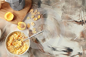 Bowl with healthy cornflakes, milk and peaches on color table