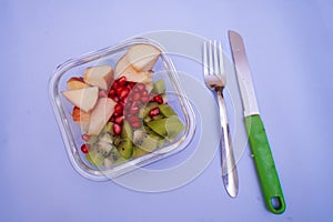 Bowl of healthy fresh fruit salad with fork and knife