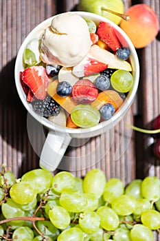 Bowl of healthy fresh fruit salad with ice cream on wooden background. Top view