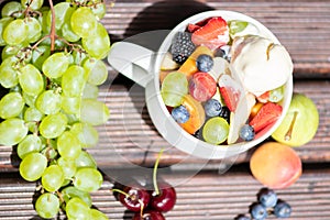 Bowl of healthy fresh fruit salad with ice cream on wooden background. Top view