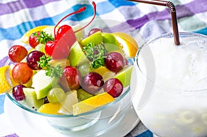 Bowl of healthy fresh fruit salad and milk on pattern of Thai hand made fabric background.