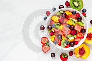 Bowl of healthy fresh fruit salad on white marble background. healthy food. top view