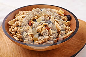 Bowl with healthy granola on wooden plate