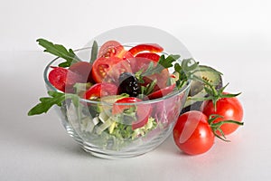 Bowl with healthy salad, cherry tomatoes, pepper, green salad, arugula, green onion, olives and avocado