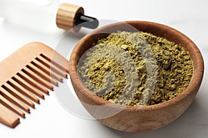 Bowl of henna powder, pipette and comb on white marble table