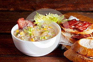 Corn chowder soup with bacon. Brown wooden background. Close-up view