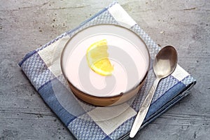 bowl of homemade strawberry yogurt ans slice of lemon.