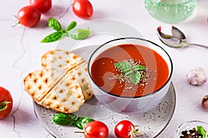 Bowl with homemade tomato soup with basil and fresh vegetables on the table