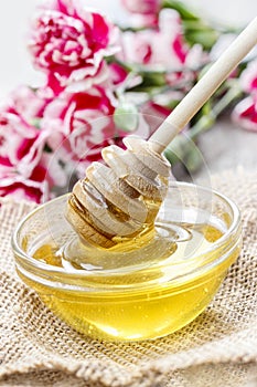 Bowl of honey and bouquet of pink carnation