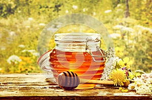 Bowl of honey with dipper in field of flowers