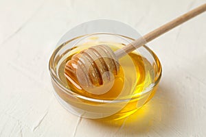 Bowl with honey and dipper on white background