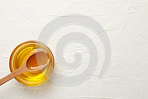 Bowl with honey and spoon on background, top view