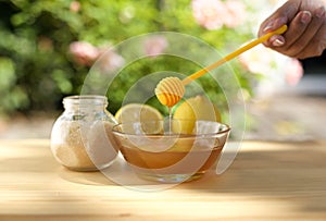 Bowl of honey and sugar and lemons on wooden table