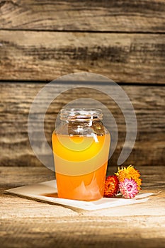 The bowl with honey on wooden table.The bank of honey stay near wooden spoon