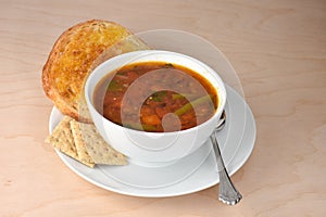 Bowl of hot garden vegetable soup, spoon, whole grain saltine cr