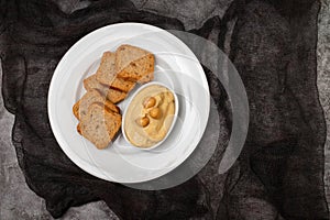 a bowl of hummus dip with mini toasts