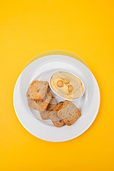 a bowl of hummus dip with mini toasts