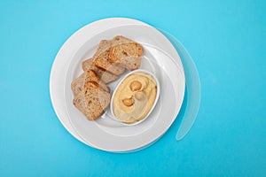 a bowl of hummus dip with mini toasts