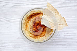 Bowl of Hummus iwith spices and pita bread on a white wooden surface, top view.