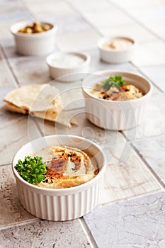 Bowl of hummus, traditional Jewish, Arabian, Middle Eastern food from chick-peas with deeps and with  pita flatbread on ceramic