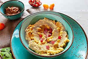 Bowl of hummus, traditional Jewish, Arabian, Middle Eastern food from chick-peas with dip tahini on grey background. Close up, top