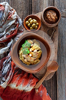 Bowl of hummus, traditional Jewish, Arabian, Middle Eastern food from chick-peas with dip tahini and olives on vintage wooden