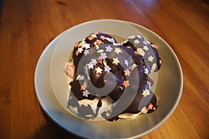 A bowl of ice cream, chocolate coating and colorful sprinkles