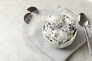 Bowl with ice cream and crumbled chocolate cookies on grey background