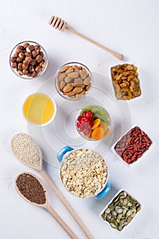 Bowl with ingredients for cooking homemade granola on white background. Healthy snak.