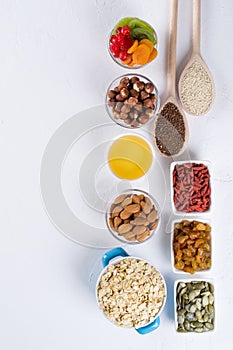 Bowl with ingredients for cooking homemade granola on white background. Healthy snak.